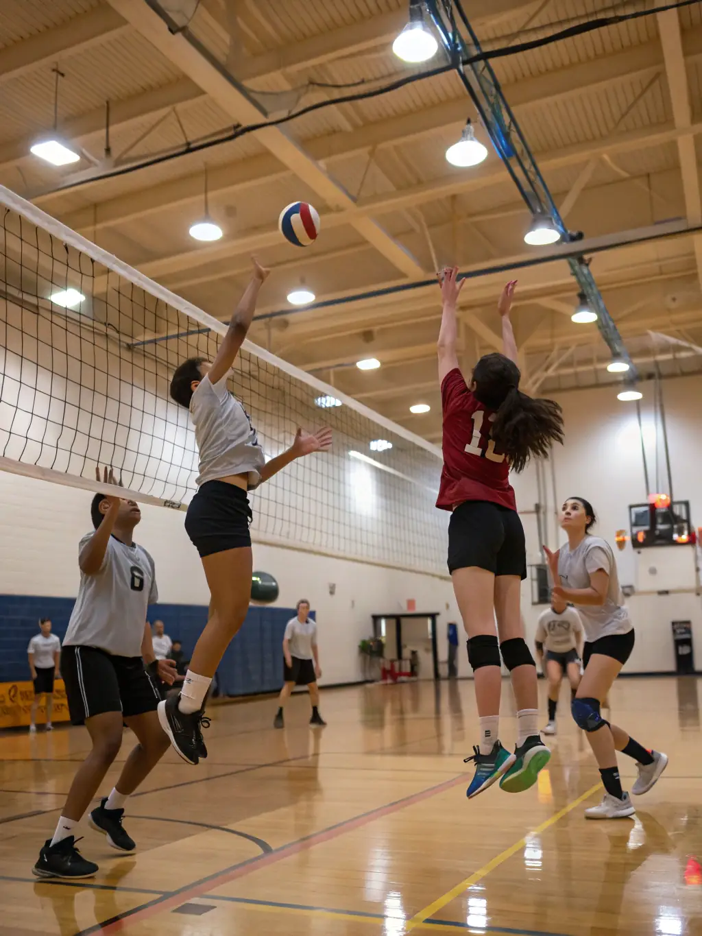 Students practicing volleyball in the school gymnasium, demonstrating coordination and teamwork in the ASS SPORTIVE LES CARDABELLES volleyball program.